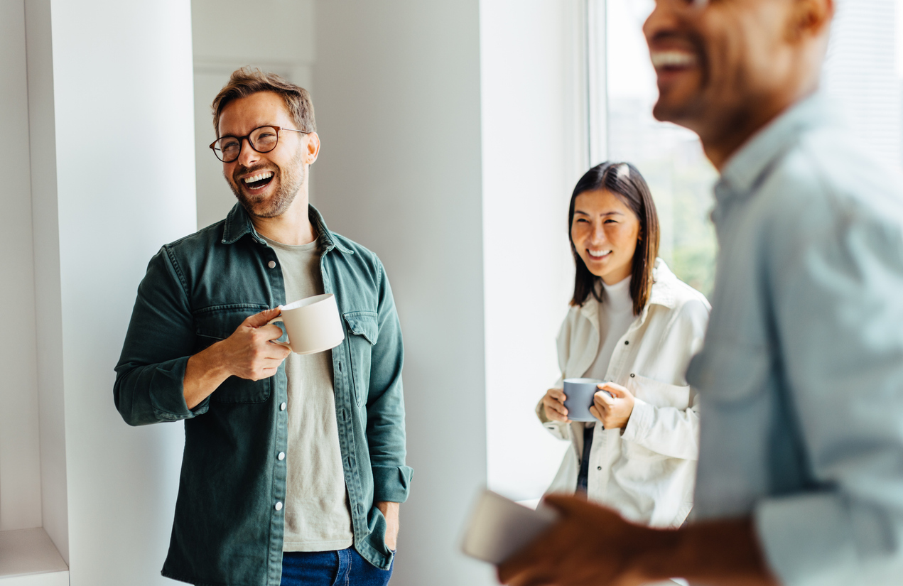 Colleagues smiling and drinking coffee together.